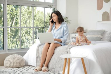 Çalışan anne ve küçük bebeği yatak odasında oyuncaklarla oynuyorlar.