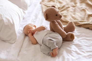 Oyuncak ayıyla evde uyuyan tatlı bir bebek.