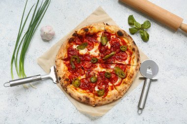 Lezzetli pizza, kesici ve arka planda bulunan malzemeler.