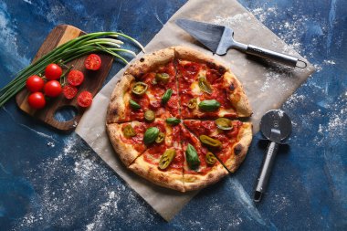 Lezzetli pizzalı kompozisyon, malzemeler ve mavi arka planda kesici.