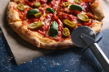 Mavi arka planda lezzetli pizza ve kesiciler, yakın plan.