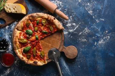 Lezzetli pizzalı kompozisyon, malzemeler ve mavi arka planda kesici.