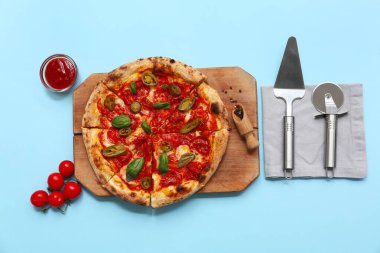 Lezzetli pizza, spatula ve mavi arka planda kesicili kompozisyon