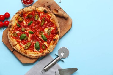 Lezzetli pizzalı kompozisyon, malzemeler ve mavi arka planda kesici.