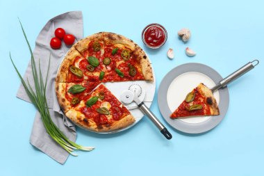 Lezzetli pizzalı kompozisyon, malzemeler ve mavi arka planda kesici.