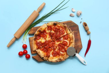 Lezzetli pizzalı kompozisyon, malzemeler ve mavi arka planda kesici.