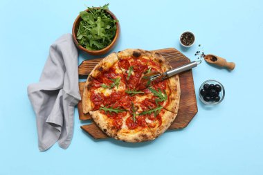 Lezzetli pizzalı kompozisyon, malzemeler ve mavi arka planda kesici.