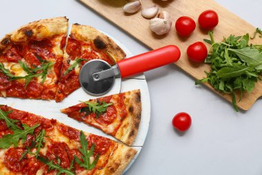 Lezzetli pizzalı kompozisyon, malzemeler ve gri arka planda kesici.