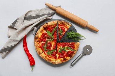 Lezzetli pizzalı kompozisyon, gri arka planda merdane ve keski.