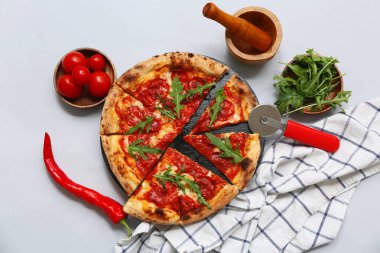 Lezzetli pizzalı kompozisyon, malzemeler ve gri arka planda kesici.