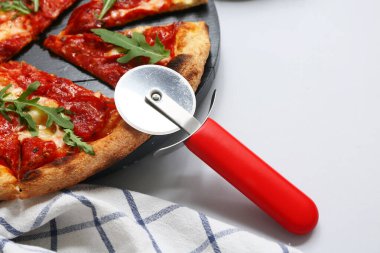 Gri arka planda lezzetli pizza ve kesici, yakın plan.