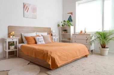 Yatak odasının içinde masalar, raf ünitesi ve çekmeceler var.