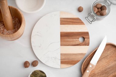 Boş kesim tahtası, mutfak aletleri ve baharatlar ışık masasında.