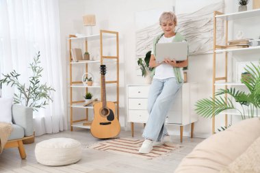 Oturma odasında laptop kullanan olgun bir kadın.