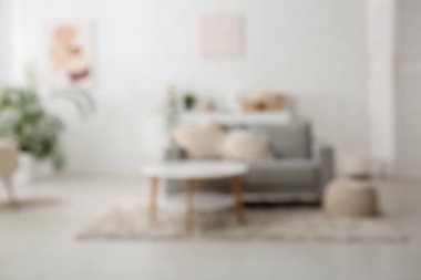 Gri kanepesi ve masası olan aydınlık oturma odasını bulanık görüyorum.