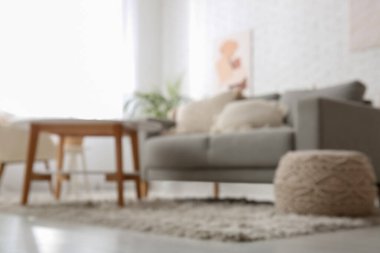 Gri kanepesi ve masası olan aydınlık oturma odasını bulanık görüyorum.