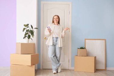 Taşındığı gün holde anahtarları, cep telefonu ve karton kutuları olan güzel bir kadın.