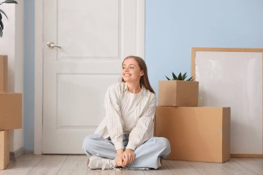 Koridorda yerde duran karton kutularla güzel genç bir kadın.