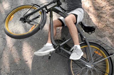 Genç adam parkta bisikletinden düşmüş, yakın plan.