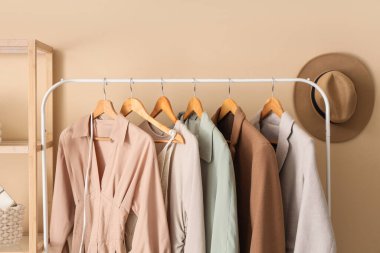 Bej duvarın yanında giysi askılığı ve raf ünitesi olan modern giyinme odasının içinde, yakın plan.