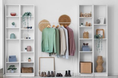 Giysi askılığı ve rafları beyaz duvarın yanında olan modern soyunma odasının içinde.