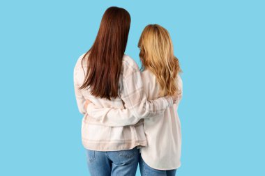 Güzel genç bir kadın mavi arka planda annesine sarılıyor. Uluslararası Sarılma Günü