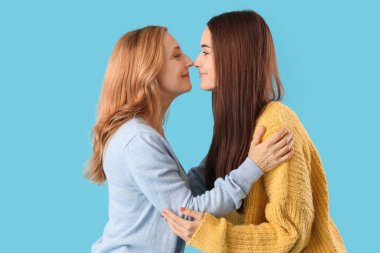 Annesi mavi arka planda burunlara dokunan güzel bir genç kadın.