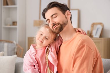 Evdeki kanepede otururken babasına sarılan tatlı küçük kız. Uluslararası Sarılma Günü