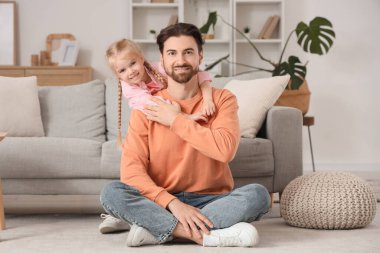 Evde yerde otururken babasına sarılan tatlı küçük kız. Uluslararası Sarılma Günü