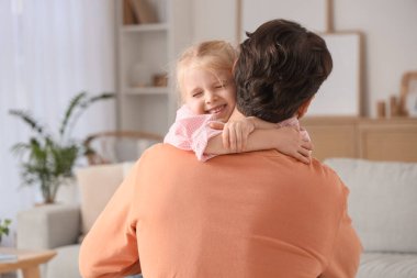 Evdeki kanepede otururken babasına sarılan tatlı küçük kız. Uluslararası Sarılma Günü