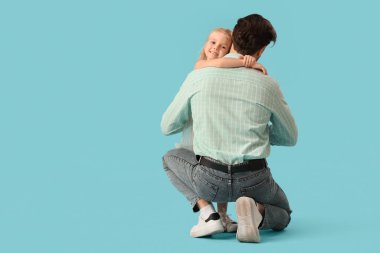 Küçük tatlı bir kız mavi arka planda babasına sarılıyor. Uluslararası Sarılma Günü