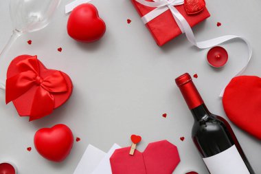 İçinde kalpler, mumlar ve gri arka planda şarap bulunan hediye kutularından yapılmış çerçeve. Sevgililer Günü kutlaması