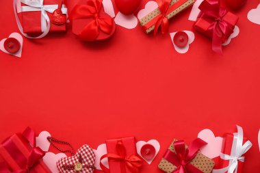 İçinde kağıt kalpler ve kırmızı arka planda mumlar olan hediye kutuları. Sevgililer Günü kutlaması