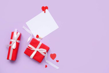 İçinde hediye kutuları ve eflatun kaplamalı kağıt kalpler olan boş bir kart. Sevgililer Günü kutlaması