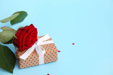 Hediye kutusu ve mavi arka planda güzel kırmızı bir gül. Sevgililer Günü kutlaması