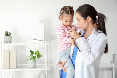 Steteskoplu kadın çocuk doktoru ve klinikte küçük tatlı bir kız.