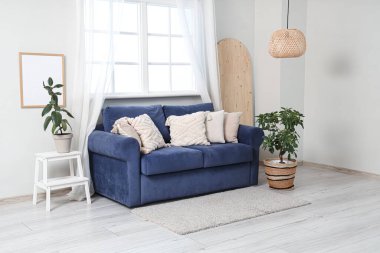 Oturma odasının iç tarafında rahat bir kanepe ve çiçek var.