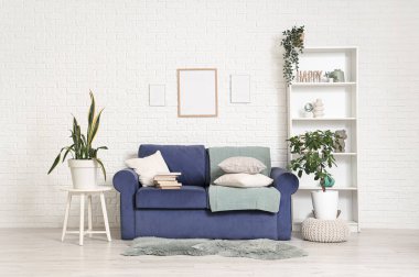 Oturma odasının iç tarafında kitap ve çiçeklerle dolu rahat bir kanepe.