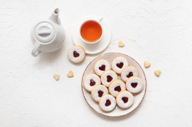 Plate with sweet cookies and cup of tea on white background. Valentine's Day celebration clipart