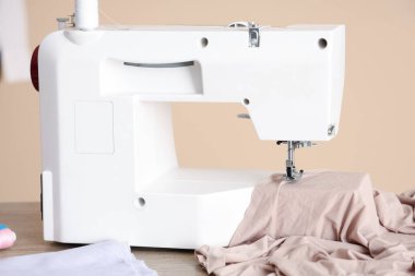 Atölyede bej kumaşlı modern dikiş makinesi, yakın plan.