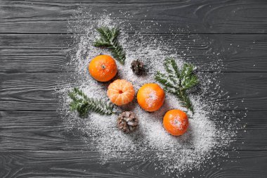 Mandallı tatlı mandallar, köknar dalları ve gri ahşap arka planda kar.