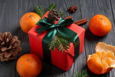 Tatlı mandallı hediye kutusu, gri ahşap arka planda köknar dalları ve koniler, yakın plan.