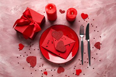 Zarflı güzel bir masa, hediye kutusu ve pembe arka planda yanan mumlar. Sevgililer Günü kutlaması