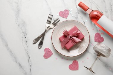 Hediye kutusu ve beyaz arka planda bir şişe şarap olan güzel bir masa. Sevgililer Günü kutlaması