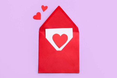 Leylak arka planında kağıt kalpler olan bir zarf. Sevgililer Günü kutlaması