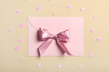 Pembe fiyonklu zarf ve bej arka planda kalpler. Sevgililer Günü kutlaması