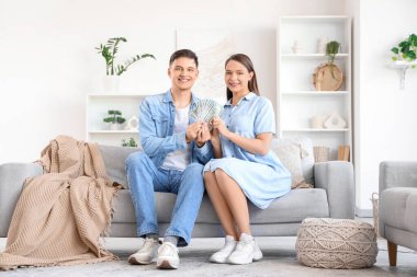 Parası olan genç çift evdeki kanepede oturuyor.