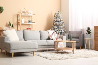 Oturma odasının içinde Noel ağaçları, kanepe ve koltuk var.