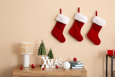 Toplu XMAS sözcükleri, oyuncak köknar ağaçları, lamba ve raflarda bej duvarın yanında kitaplar.