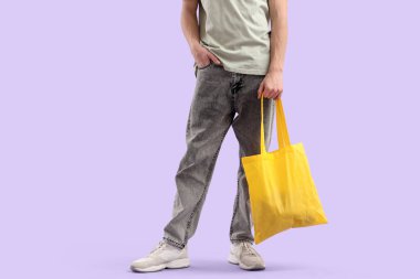 Leylak arkaplanlı sarı tekstil çantalı genç adam